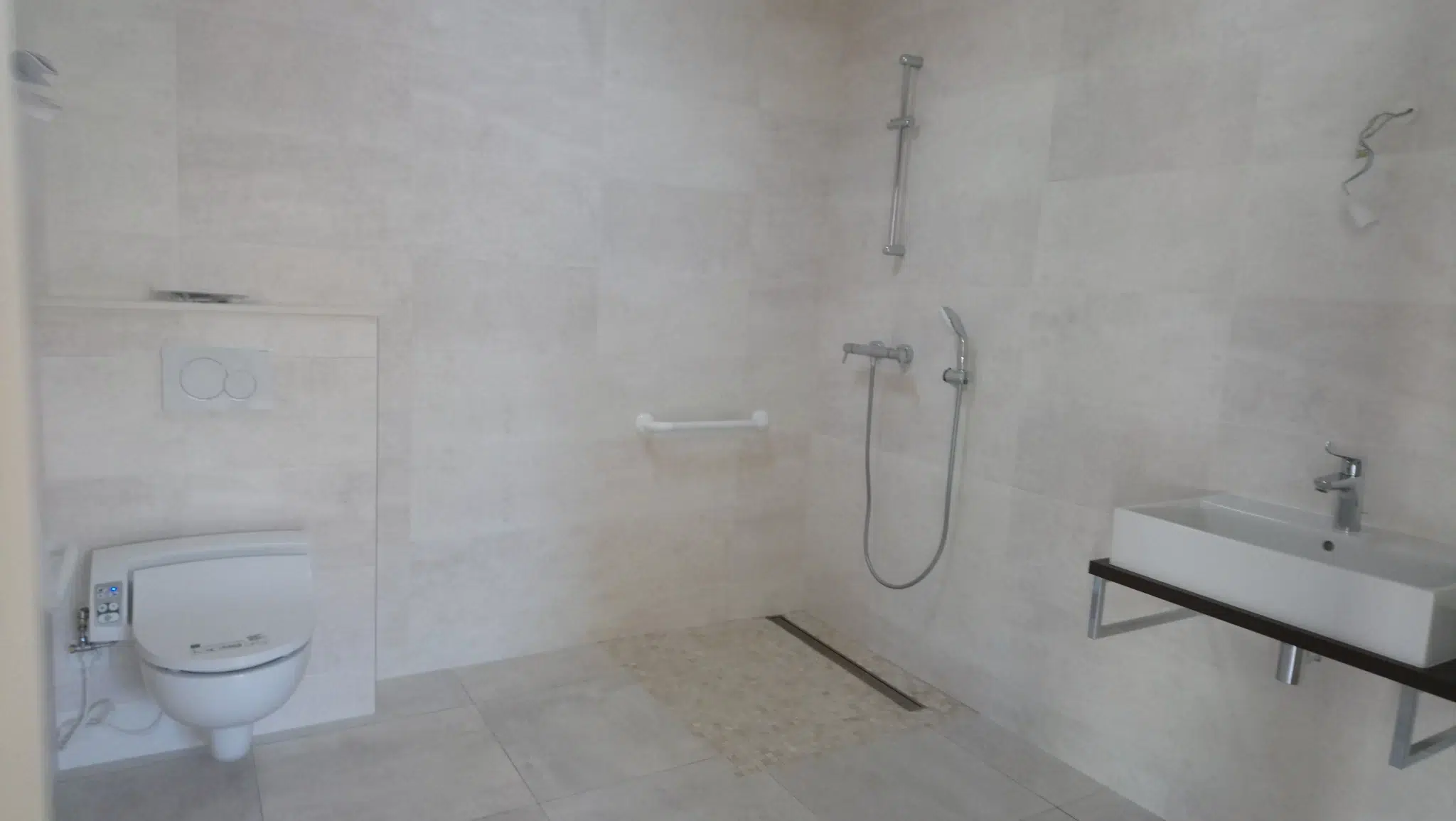 Salle de bain accessible avec douche italienne et WC.
