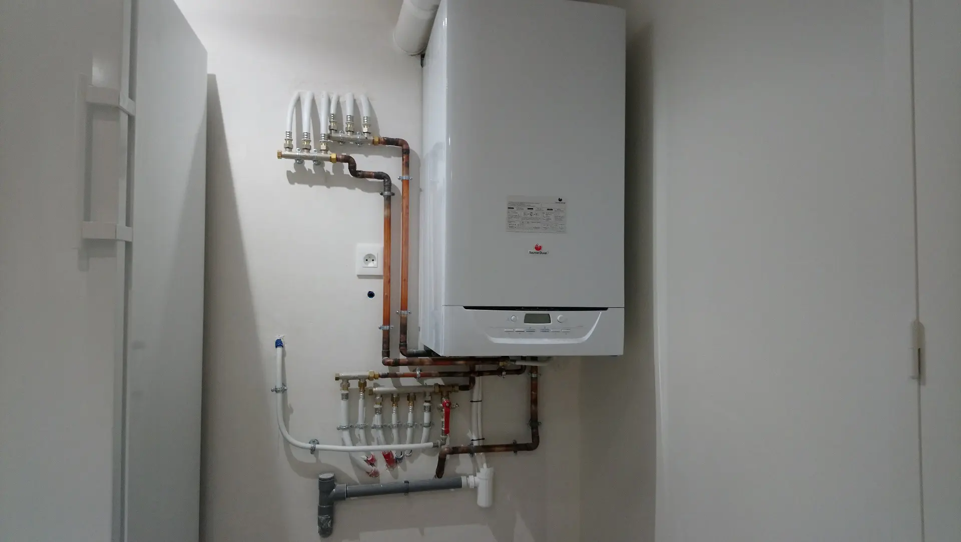 Chaudière murale, tuyauterie visible.