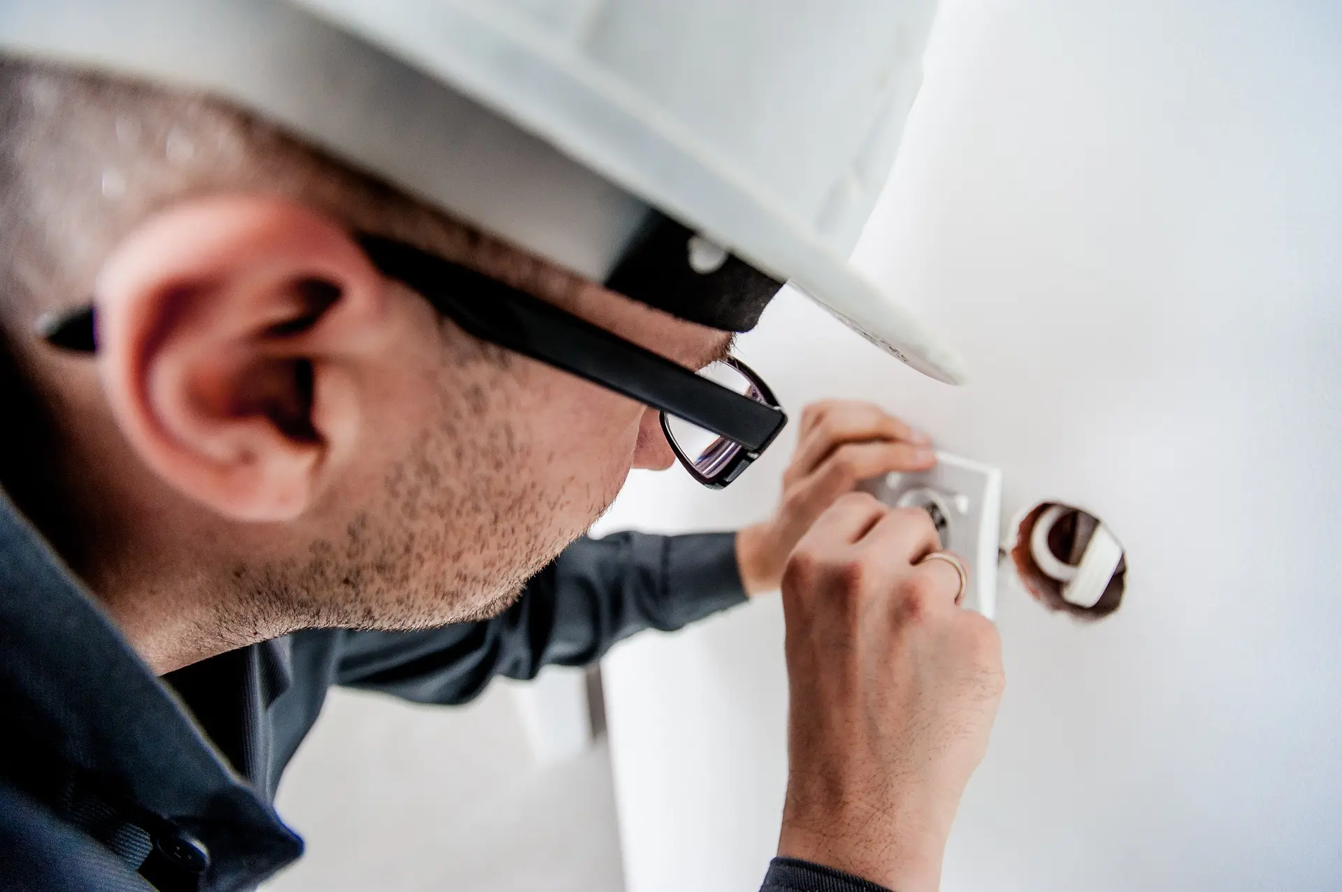 Électricien installant une prise murale.