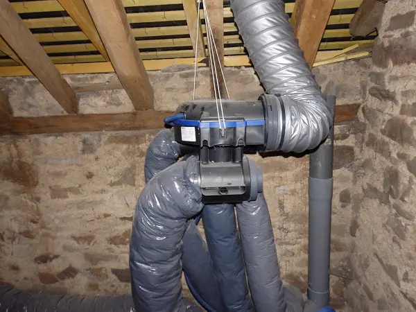 Installation de conduits dans un grenier en bois.