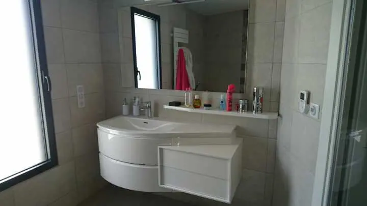 Salle de bain moderne avec lavabo et miroir.