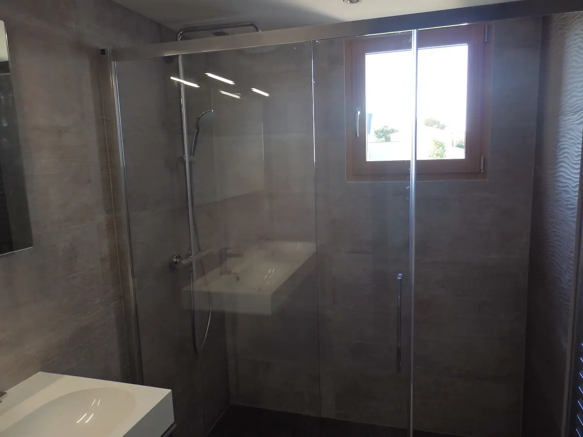 Salle de bain moderne avec douche et fenêtre.
