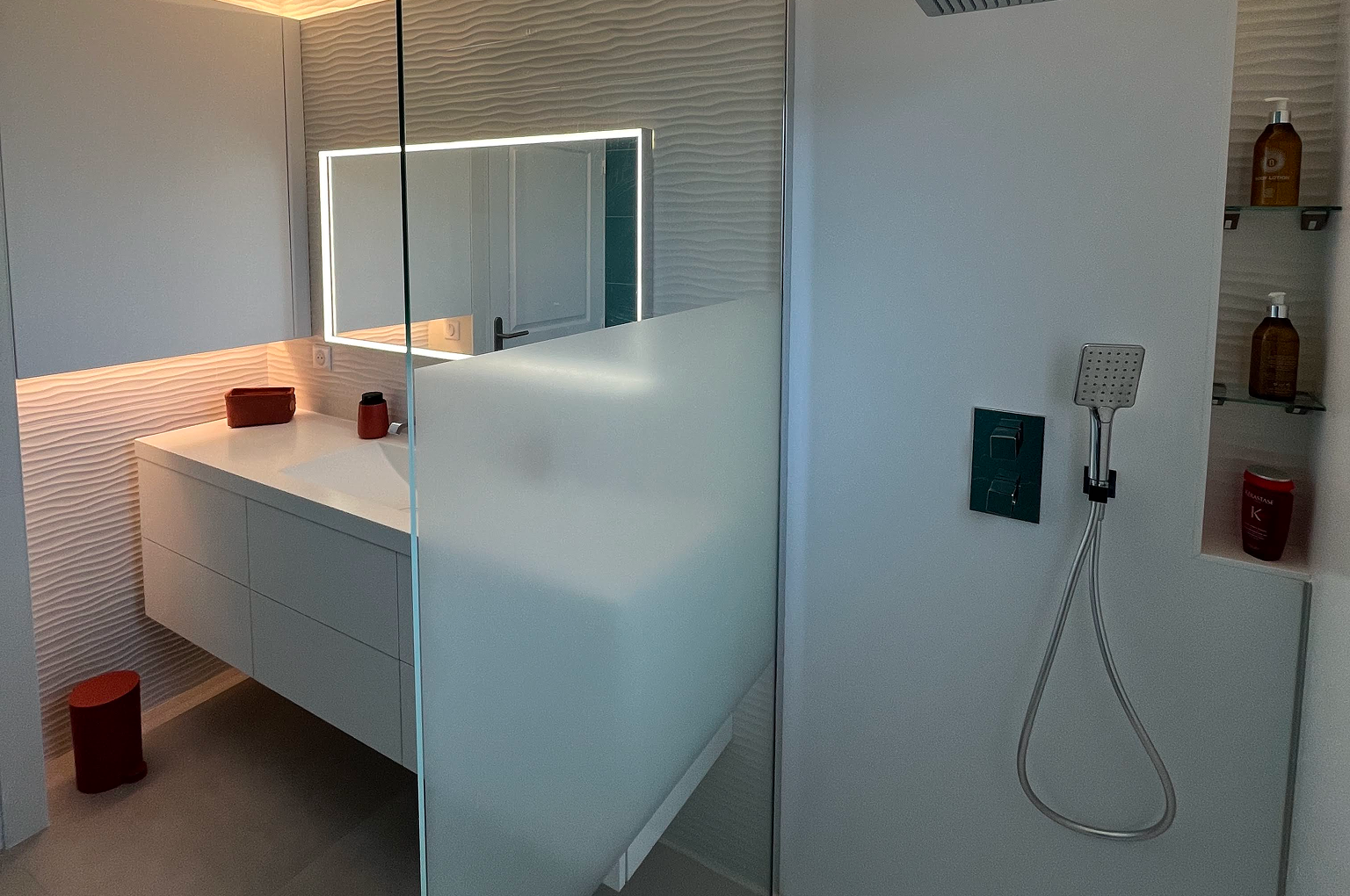 Salle de bain moderne avec douche et lavabo.