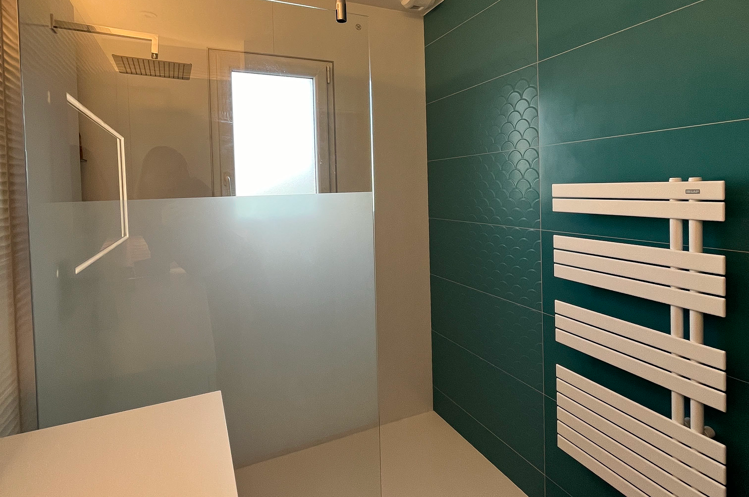 Douche moderne avec paroi vitrée et carrelage turquoise.